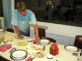 Foto: Ein Kursteilnehmer deckt den grossen Esstisch ein.